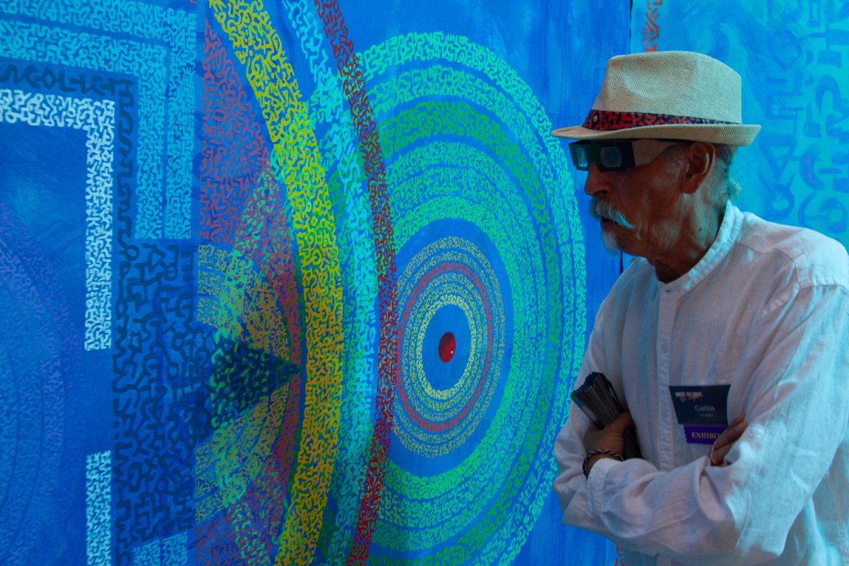 Artist Carlos Grasso, looks at his tapestry with 3D glasses at the Unite to Light fundraiser on Oct. 19 at the Community Arts Workshop in Santa Barbara, Calif. Grasso believes his original  3D tapestries allow viewers to explore their interpretation of the world and themselves by using unique and ancient shapes on the tapestries. 